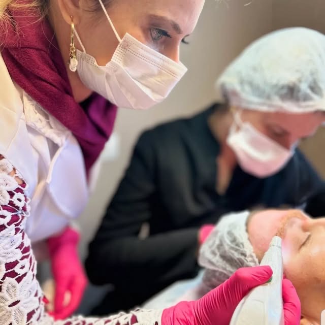 Duas profissionais da clínica realizando um procedimento facial